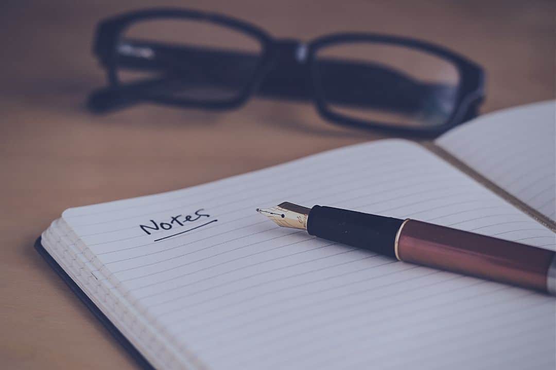 notebook, pen and glasses on table