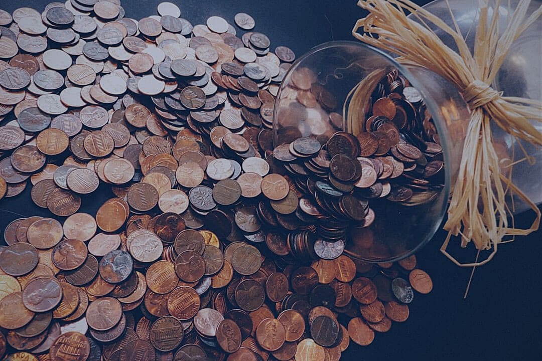 Coins spilling out of a jar and onto a table