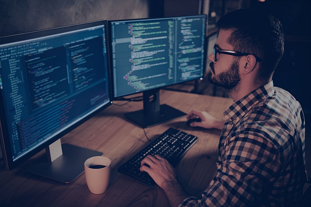 Man working in front of 2 computer monitors