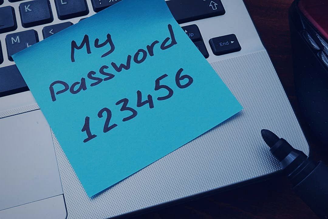 weak password written on note stuck to laptop