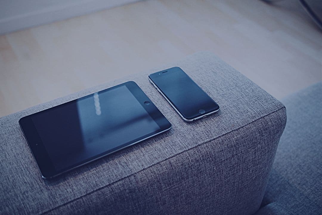 Smartphone and tablet sitting side by side on sofa