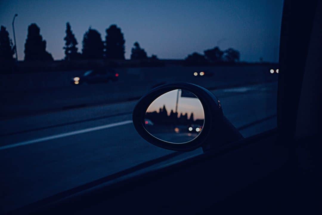 View from side view mirror or car driving at twilight