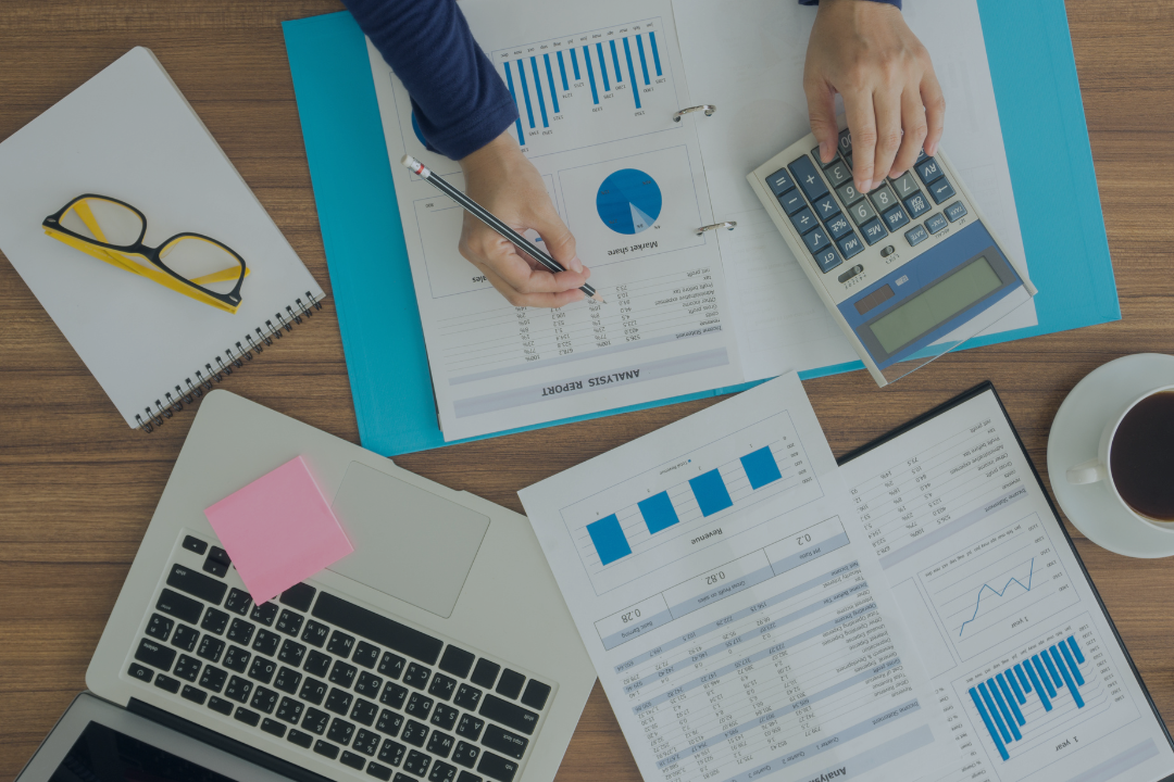 Busy accountant's desk with computer, calculator and reports