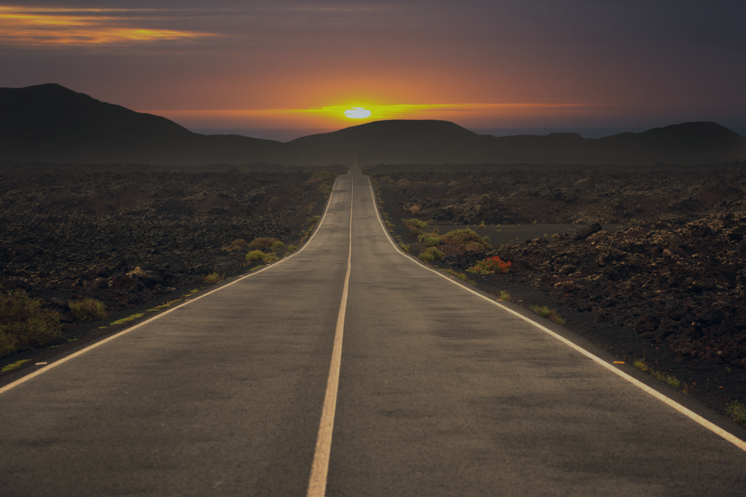 Long stretch of road with sunset on the horizon